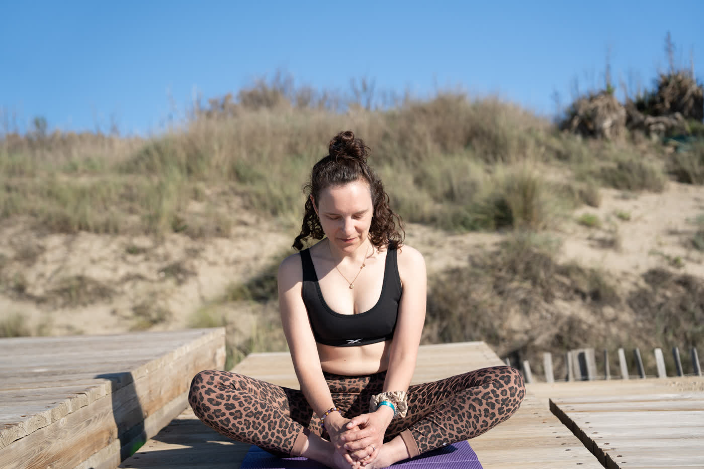 Madeline assise en tailleur devant les dunes